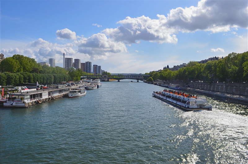 1 - A view of the Seine River in Paris, France, captured from a bridge looking down the water with tour boats and riverside buildings